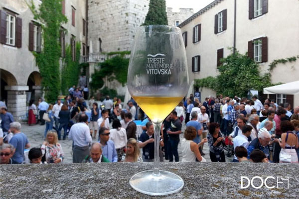 Bicchiere di Mare Morje Vitovska su sfondo di castello di Duino